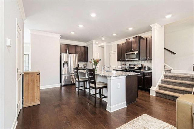 2700 Norwich Trce, Snellville, GA 30078 - kitchen featuring appliances with stainless steel finishes, dark brown cabinets, a breakfast bar, tasteful backsplash, and dark wood finished floors