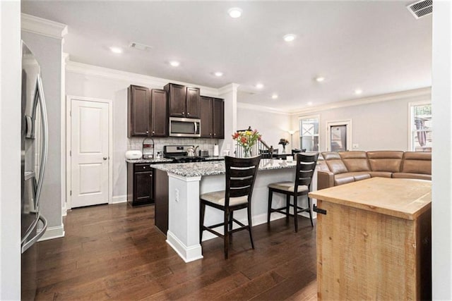 2700 Norwich Trce, Snellville, GA 30078 - kitchen with stainless steel appliances, a kitchen bar, dark brown cabinetry, an island with sink, and decorative backsplash