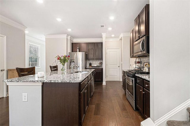 2700 Norwich Trce, Snellville, GA 30078 - kitchen featuring appliances with stainless steel finishes, crown molding, dark brown cabinetry, dark wood-type flooring, and an island with sink