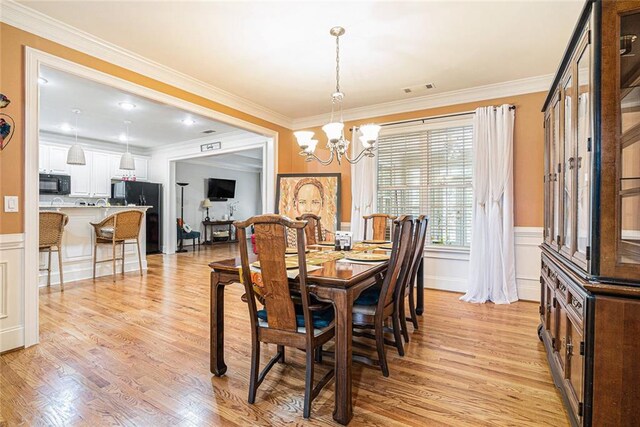 725 Windsor Place Cir SW, Grayson, GA 30017 - dining room featuring a chandelier, light wood-style flooring, ornamental molding, a wainscoted wall, and a decorative wall