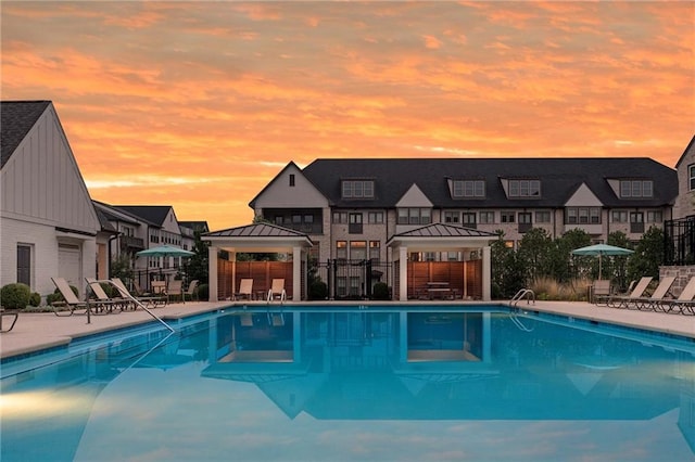 pool at dusk featuring a gazebo and a patio area