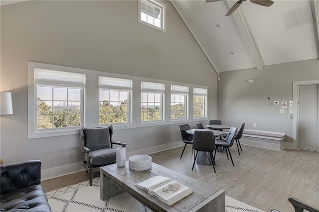 living room with elevator, ceiling fan, beamed ceiling, high vaulted ceiling, and light wood-type flooring