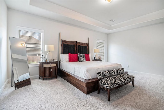 bedroom featuring a tray ceiling, baseboards, and carpet