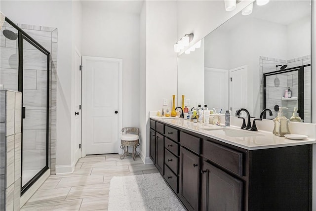 bathroom featuring double vanity, a sink, baseboards, and a stall shower