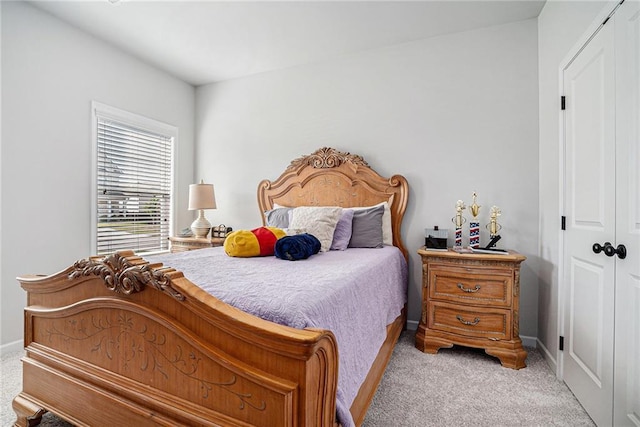 bedroom with baseboards, a closet, and light carpet