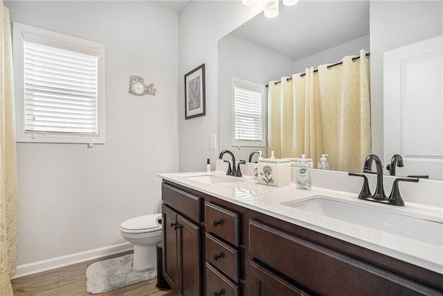 full bath with a sink, baseboards, toilet, and wood finished floors