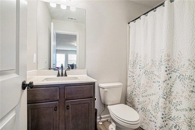 bathroom featuring vanity, toilet, a shower with shower curtain, wood finished floors, and visible vents