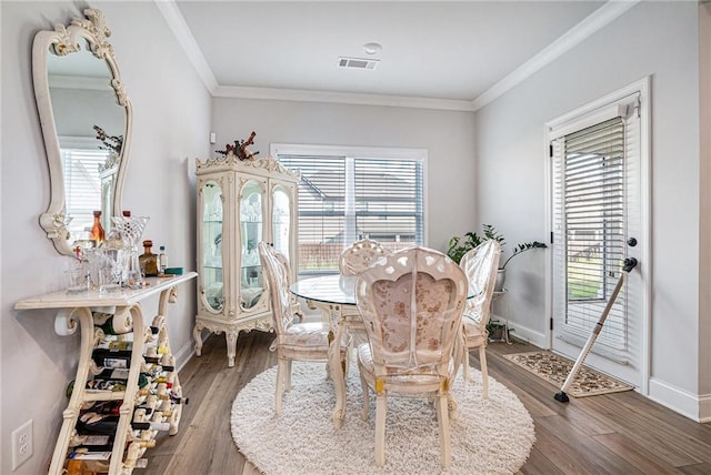 dining space with crown molding, baseboards, wood finished floors, and visible vents
