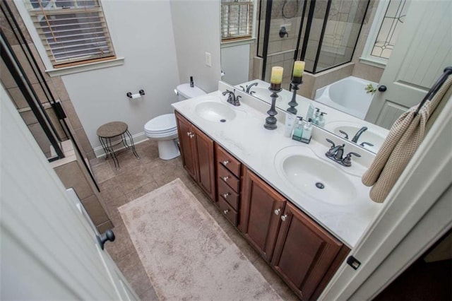 full bathroom featuring a bath, double vanity, toilet, and a sink