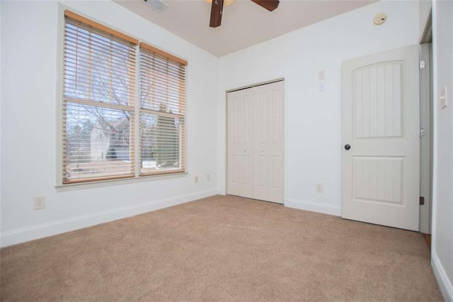 unfurnished bedroom featuring a closet, a ceiling fan, baseboards, and carpet floors