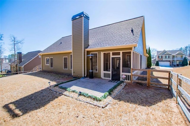 rear view of house featuring fence, roof with shingles, a sunroom, a chimney, and a patio area