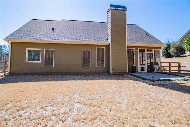 back of house with a patio, a shingled roof, a chimney, and fence