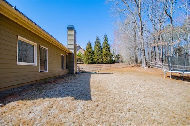 view of yard featuring a trampoline and fence