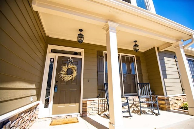 doorway to property featuring a porch and stone siding