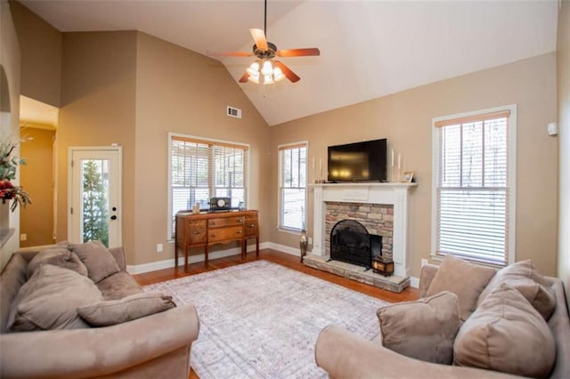 living area featuring visible vents, baseboards, a fireplace, wood finished floors, and a ceiling fan