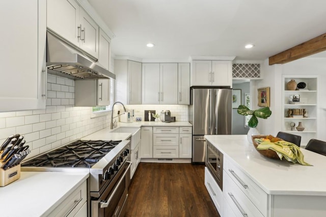 kitchen with appliances with stainless steel finishes, a sink, light countertops, under cabinet range hood, and recessed lighting