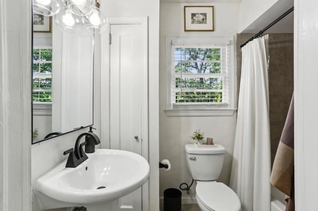 bathroom with a shower with shower curtain, toilet, and a sink