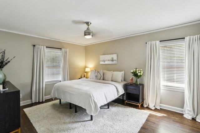 bedroom with crown molding, baseboards, a ceiling fan, and dark wood-type flooring