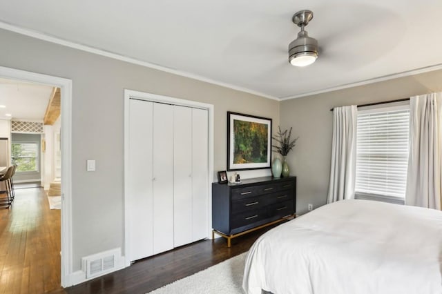 bedroom featuring visible vents, crown molding, a closet, baseboards, and dark wood-style floors