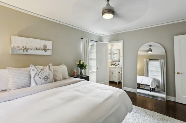 bedroom with crown molding, baseboards, wood finished floors, and connected bathroom