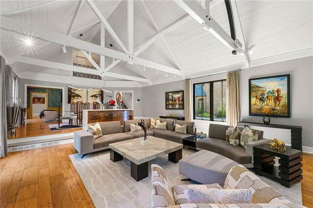 living room featuring beamed ceiling, light wood-type flooring, high vaulted ceiling, and wooden ceiling