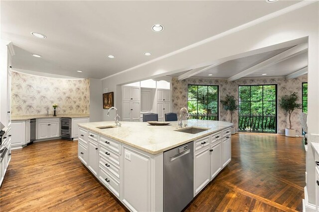 kitchen with light stone counters, a center island with sink, sink, and stainless steel dishwasher