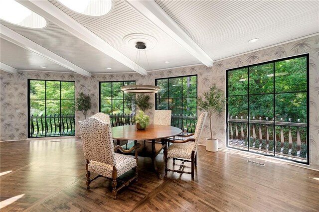 dining room featuring beamed ceiling, hardwood / wood-style floors, and a wealth of natural light