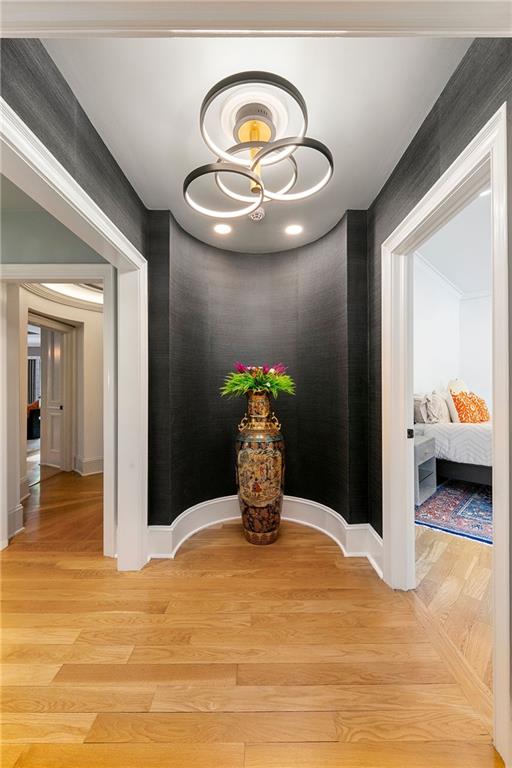 corridor featuring an inviting chandelier and light hardwood / wood-style floors