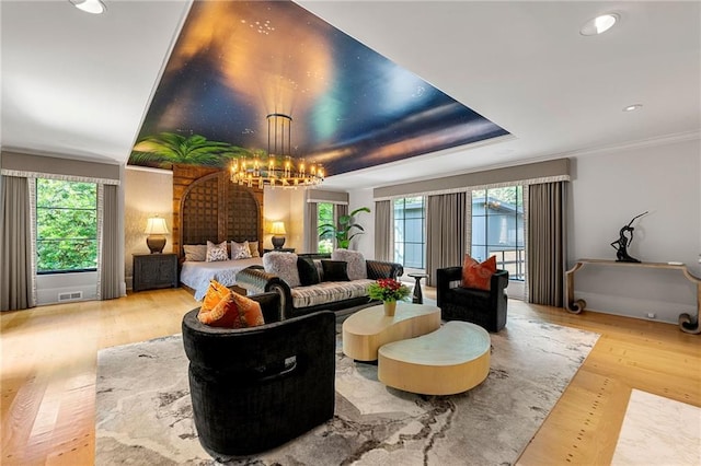 living room with light wood-type flooring, crown molding, a chandelier, and plenty of natural light