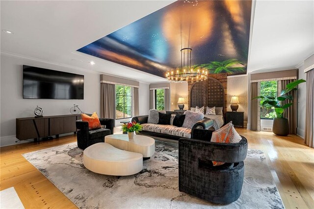 living room with ornamental molding, an inviting chandelier, and light hardwood / wood-style flooring