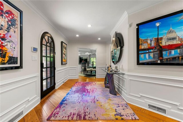 entrance foyer with crown molding and light hardwood / wood-style floors