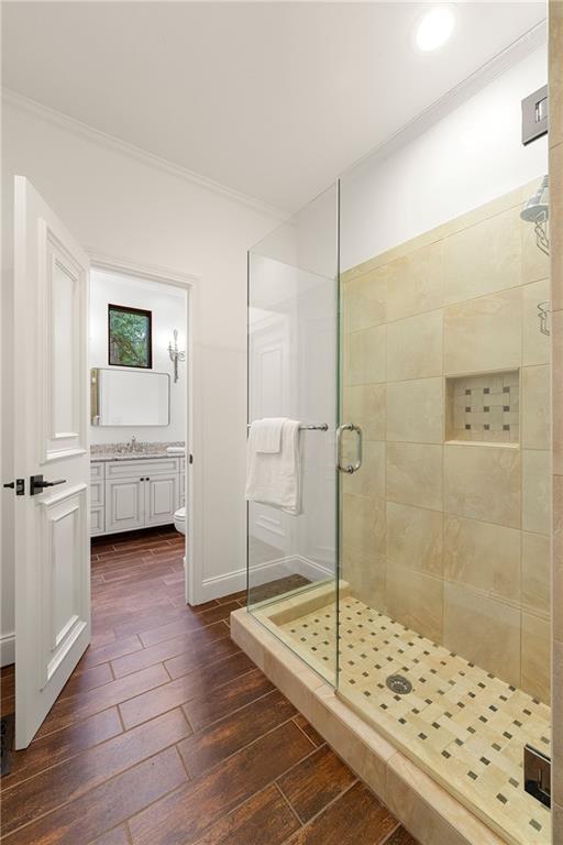 bathroom with hardwood / wood-style flooring, an enclosed shower, crown molding, vanity, and toilet