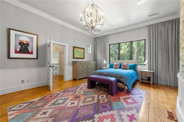 bedroom featuring light hardwood / wood-style flooring, a chandelier, and ornamental molding