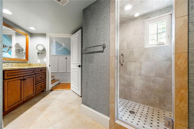 bathroom with tile patterned flooring, walk in shower, and vanity