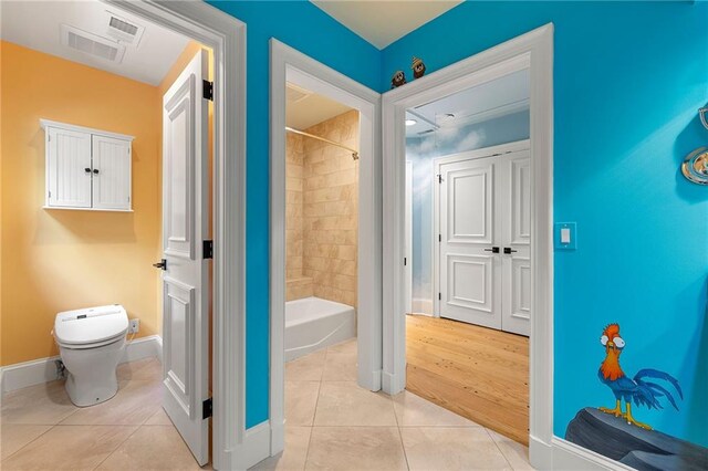 bathroom with tile patterned flooring, toilet, and tiled shower / bath