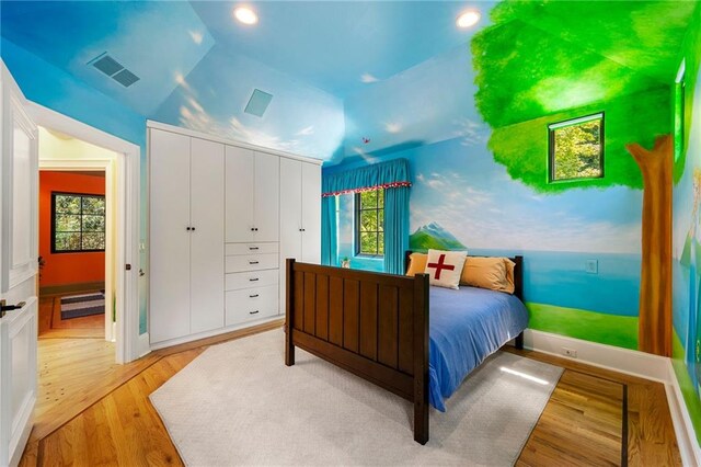 bedroom featuring light wood-type flooring, a closet, and lofted ceiling