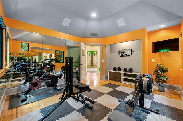 exercise room featuring lofted ceiling and light wood-type flooring