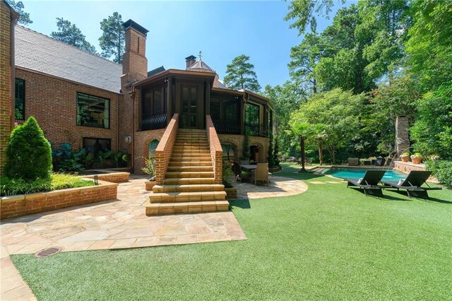 back of property with a sunroom, a yard, and a patio