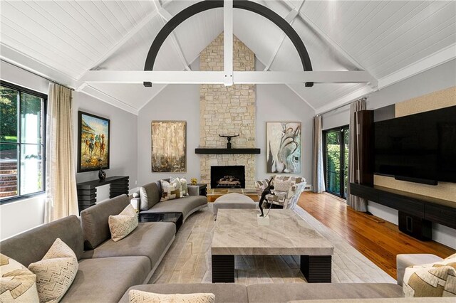 living room featuring light hardwood / wood-style floors, a fireplace, high vaulted ceiling, and plenty of natural light