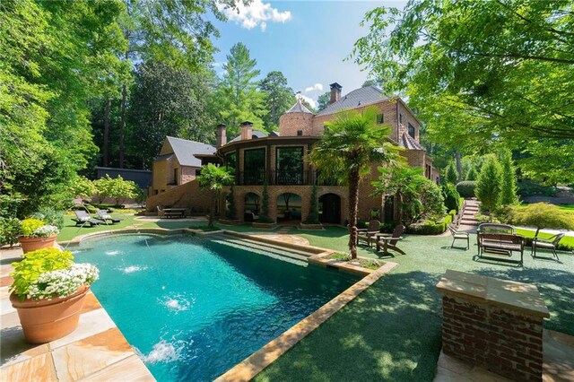 view of swimming pool with an outdoor fire pit, pool water feature, and a patio area