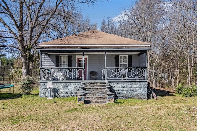 bungalow featuring a trampoline, a porch, and a front lawn