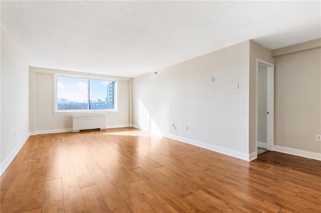 2479 Peachtree Rd NE Unit 605, Atlanta, GA 30305 - spare room with radiator heating unit, wood finished floors, baseboards, and a textured ceiling