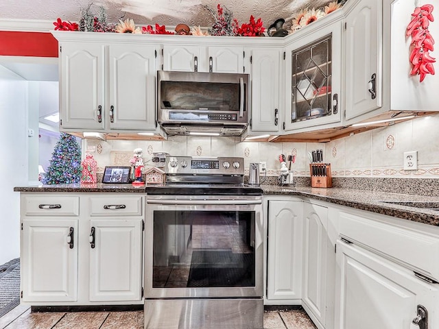 kitchen featuring dark stone countertops, white cabinetry, backsplash, and appliances with stainless steel finishes