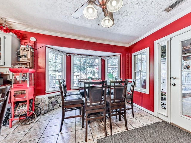 tiled dining space featuring ceiling fan, a textured ceiling, and ornamental molding