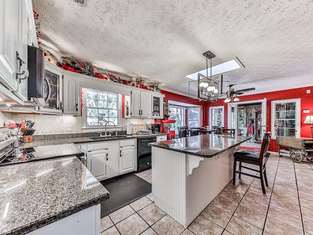 kitchen with stainless steel appliances, a textured ceiling, sink, white cabinets, and a center island