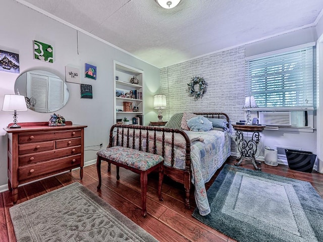 bedroom featuring cooling unit, dark wood-type flooring, a textured ceiling, and brick wall