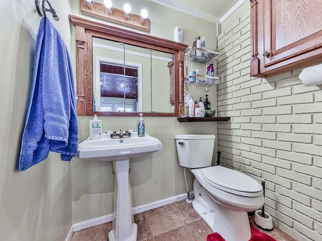 bathroom featuring brick wall, toilet, and crown molding