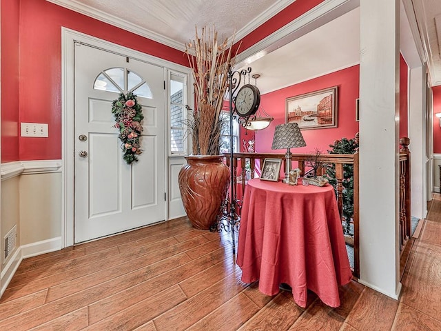 entrance foyer with hardwood / wood-style flooring, a textured ceiling, and ornamental molding