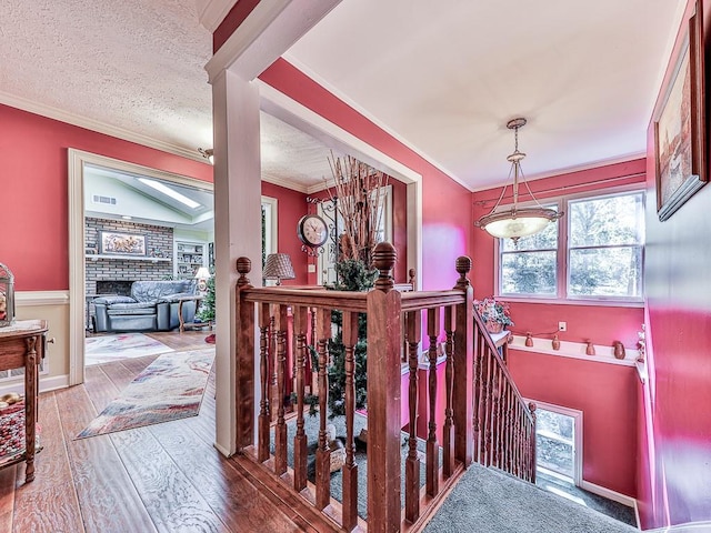 staircase with wood-type flooring, a textured ceiling, a skylight, and crown molding