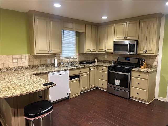 kitchen with tasteful backsplash, stainless steel appliances, dark hardwood / wood-style flooring, light stone countertops, and sink